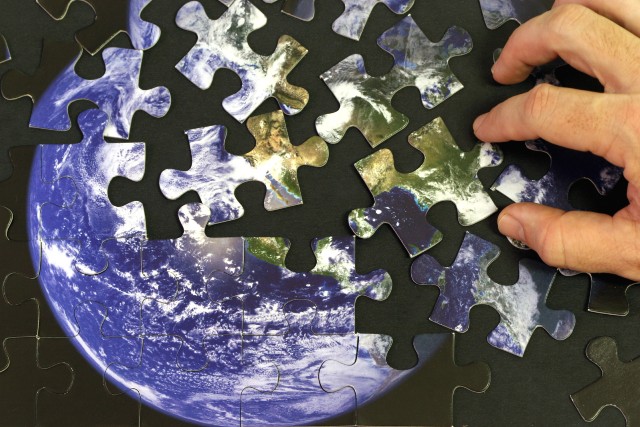 A person putting together a puzzle of the earth