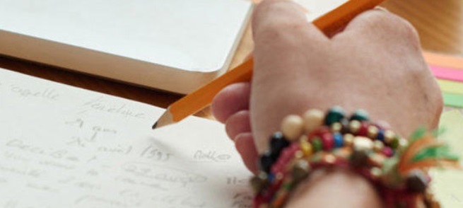 Image of a hand holding a pencil writing on paper