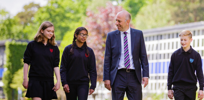 Image of a teacher walking with three secondary students outside