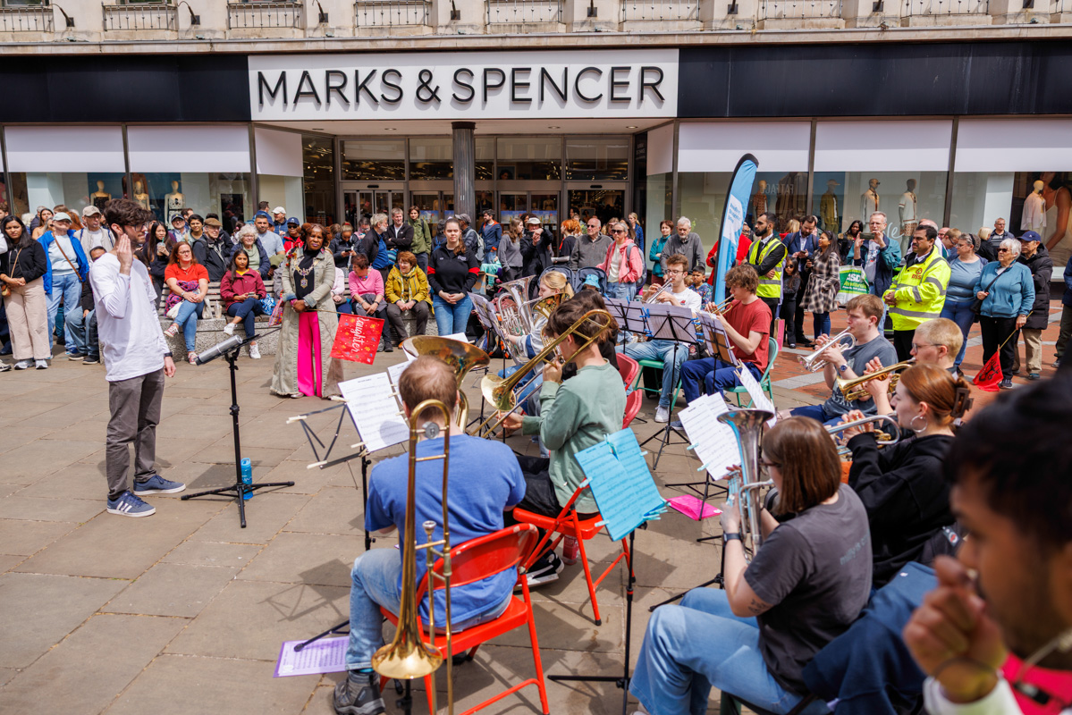 Crowd watches brass band playing in highstreet