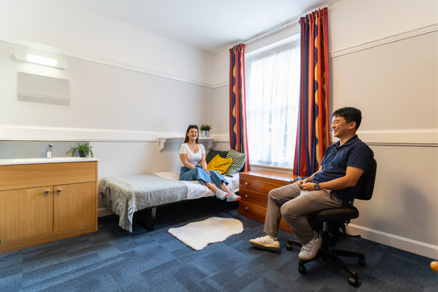 Two students sat in a bedroom