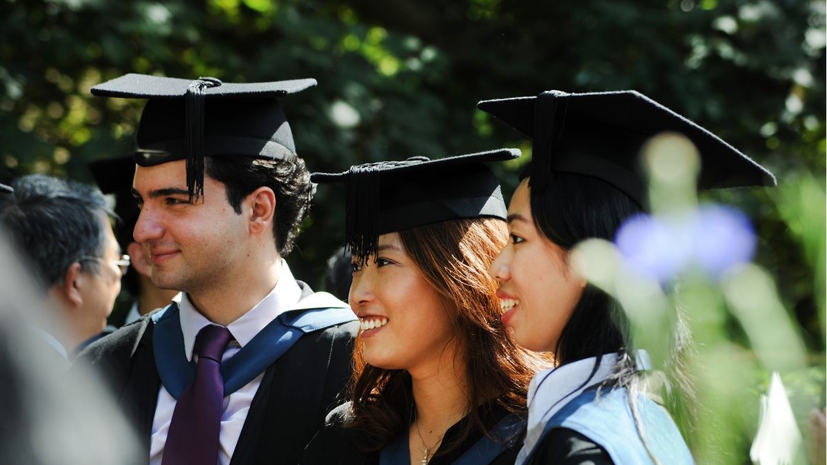 Three students wearing graduation caps and gowns