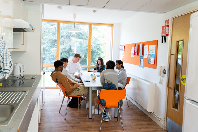 Students sat around table in kitchen